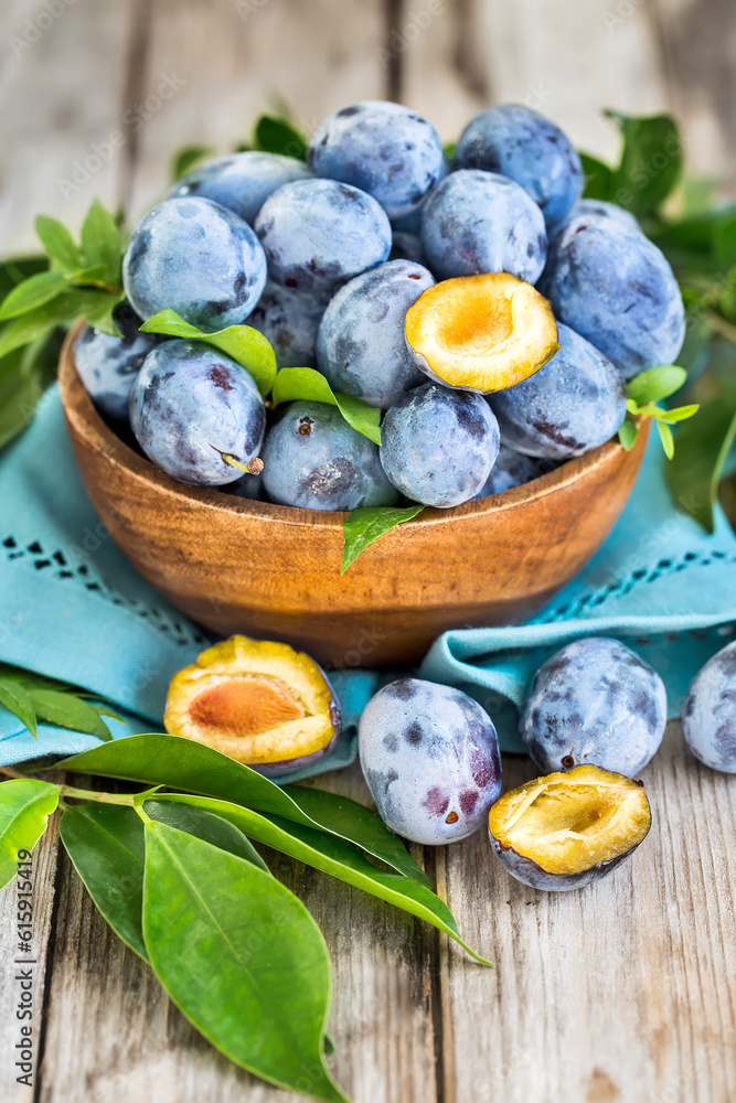 Wall mural fresh plums (prunes) in wooden bowl on old wooden background