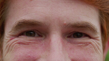 Man with serious judgemental emotion macro close-up eyes. A male person frowning looking at camera...