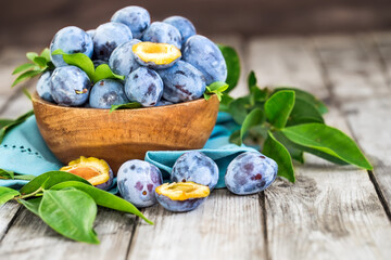 Fresh plums (prunes) in wooden bowl on old wooden background