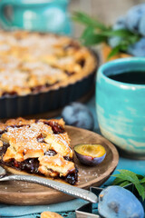 Homemade traditional plum pie with cinamon and almonds with coffee on old wooden background