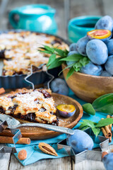 Homemade traditional plum pie with cinamon and almonds with coffee on old wooden background