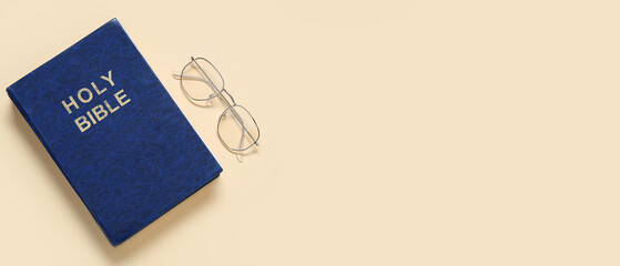 Holy Bible and glasses on beige background with space for text