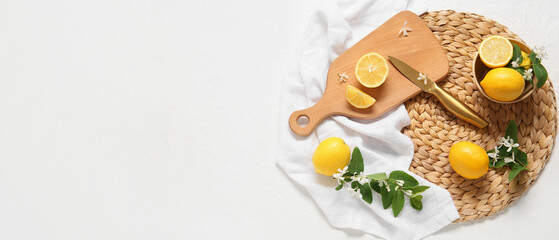 Bowl and cutting board with knife, fresh lemons and blooming branches on white background with space for text