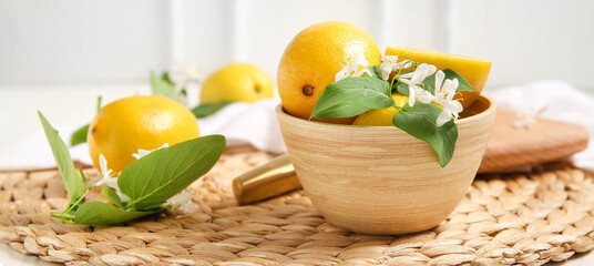 Bowl with fresh lemons and blooming branches on white table