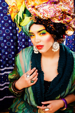 beauty bright woman with creative bright make up, many shawls on head like cubian, ethno look closeup