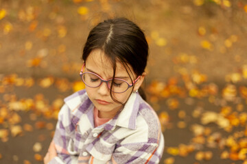 Little girl with eyeglasses in the autumn park. Selective focus.