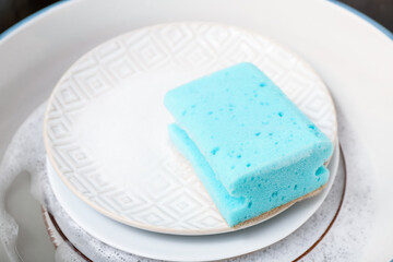 Dishes with cleaning sponge in sink, closeup