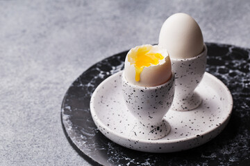 Close up view of two soft boiled eggs in eggcups on marble plate. Side view, copy space