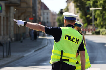 Policjant ruchu drogowego w białych rękawiczkach kieruje ruchem drogowym w mieście.