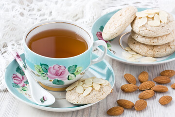 Porcelain cup of tea with almond cookies and almonds slices