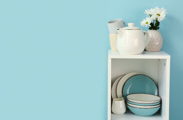 Kitchen shelving with teapot and dishes on blue background