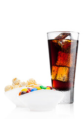 Round colorful coated sweet candies and popcorn in white bowl with cola soda drink on white background