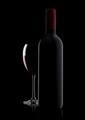 Glass of red wine with bottle with shape on black background with reflection