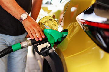 Refilling gas. Close up of man pumping gasoline fuel in car at petrol station. - obrazy, fototapety, plakaty