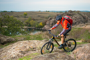 Fototapeta na wymiar Cyclist in Red Riding the Bike on the Autumn Rocky Trail. Extreme Sport and Enduro Biking Concept.