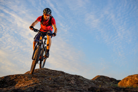 Cyclist in Red T-Shirt Riding the Bike Down the Rock on the Blue Sky Background. Extreme Sport and Enduro Biking Concept.