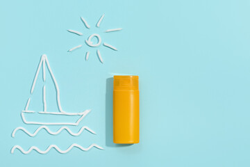 Drawings of sun and boat made with sunscreen cream on pale blue background