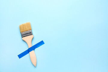 Paint brush with adhesive tape on blue background