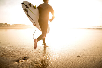 A surfer with his surfboard running to the waves