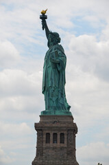 Fototapeta premium The Statue of Liberty on Liberty Island under cloudy sunny skies