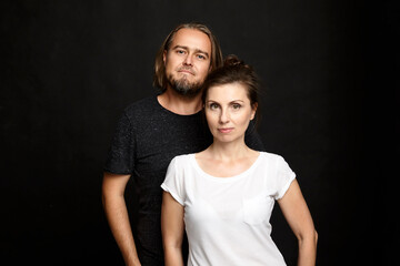 Simple portrait of partners, woman and man. Studio shot on black background.