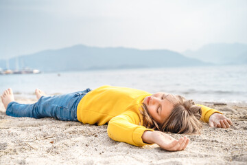 Lonely beautiful sad girl teenager lying sleeping on sand sea beach. Dreams,anxiety,worries about...