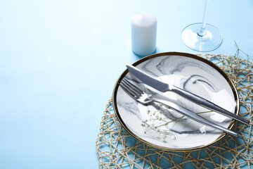 Beautiful table setting with candle and gypsophila flowers on blue background, closeup