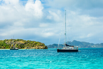 Turquoise sea and black yacht anchored at Tobago Cays, Saint Vincent and the Grenadines, Caribbean...