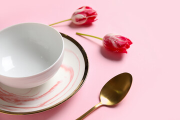 Beautiful table setting and tulips flowers on pink background, closeup
