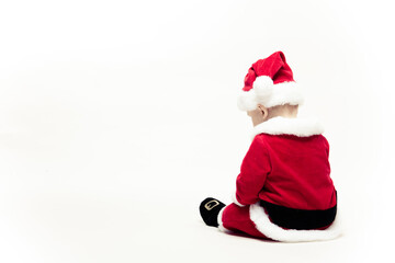 Santa Claus baby in red christmas clothes sits with his back isolated on white background