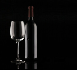 Bottle of red wine and empty glass with reflection on black background