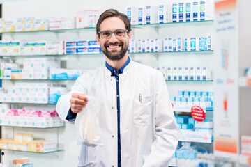 Pharmacist in pharmacy selling bag of pharmaceuticals