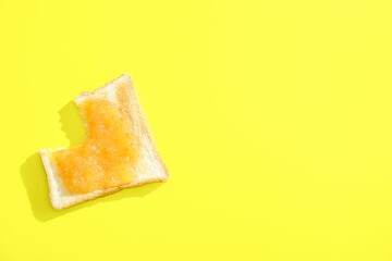Bitten toast with sweet jam on yellow background