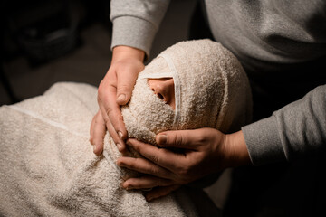 Client's face wrapped with warm towel to moisturize beard hairs before old fashioned straight razor...