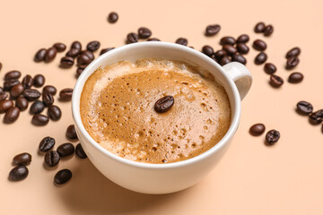 Cup of hot espresso and coffee beans on beige background