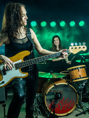 Obraz na płótnie Canvas Photo of a female bass player and drummer of a rock band playing on stage.