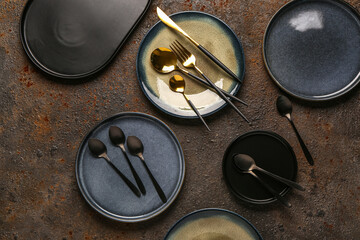Clean plates with set of cutlery on brown grunge table