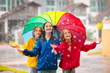 Kids play in rain. Children walk in rainy weather