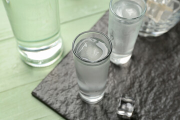 Glasses of cold vodka on green wooden background