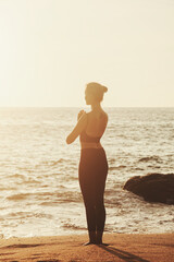 Fototapeta na wymiar Young woman does yoga for healthy lifestyle on tropical sea or ocean beach outdoors