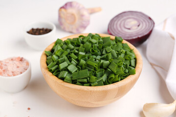 Bowl with slices of fresh scallion and onion on white background