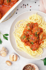 Plate of boiled pasta with tomato sauce and meat balls on white table