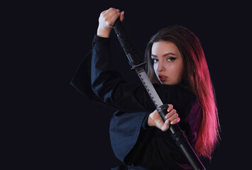 Beautiful young woman with katana on black background