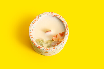 Holder with candle on yellow background