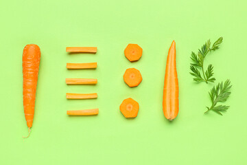Fresh carrots and slices on green background