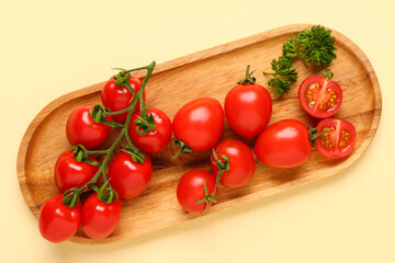 Board with fresh cherry tomatoes and parsley on yellow background