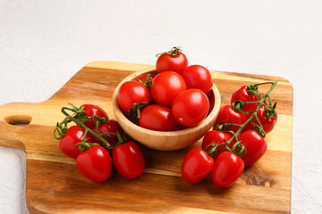 Board and bowl with fresh cherry tomatoes on white background