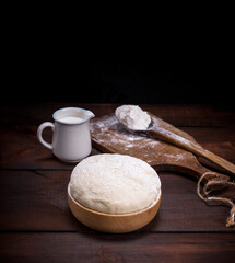 wheat yeast dough in a wooden bowl on a table, vintage toning