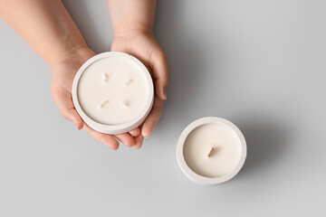 Female hands with candle on light background