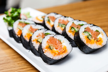 Rolls with salmon, cucumber and flying fish roe served on a plate
